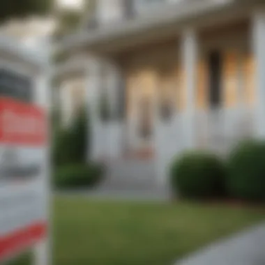 A close-up of a 'For Sale' sign in front of a modest property